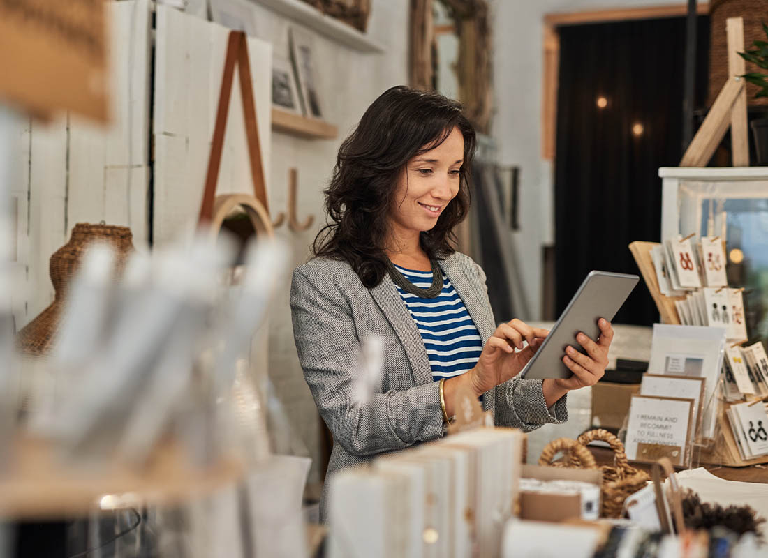Business Insurance - Smiling Young Woman Using a Tablet in Her Antique Shop